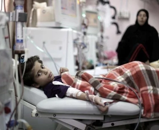 A child in a hospital bed with their mother by their side.